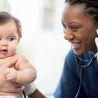 Childhood poverty - Nurse listening to a baby's heartbeat. 