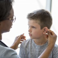 Nurse helping student with his hearing aid