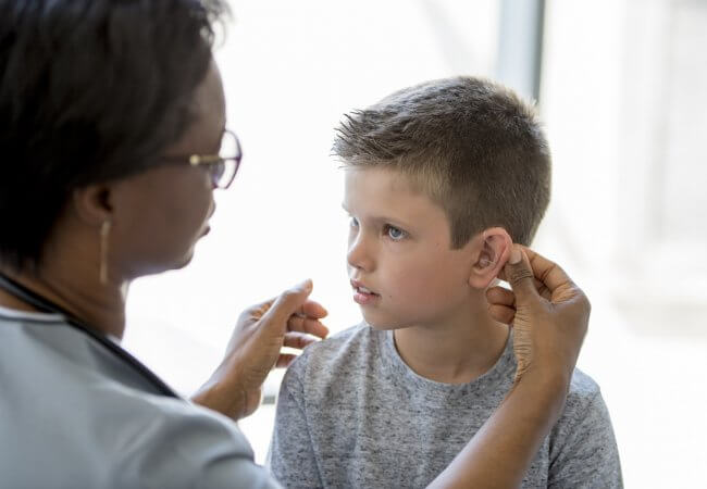 School nurse helping student with his hearing aid