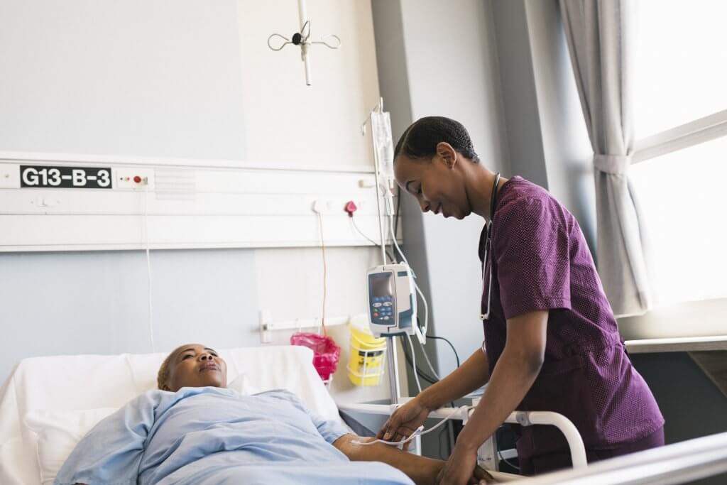 Nurse checks IV drip for female patient | Campaign for Action