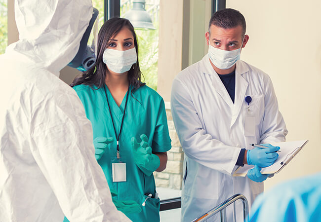 Nurses in full PPE discussing a patient case. 