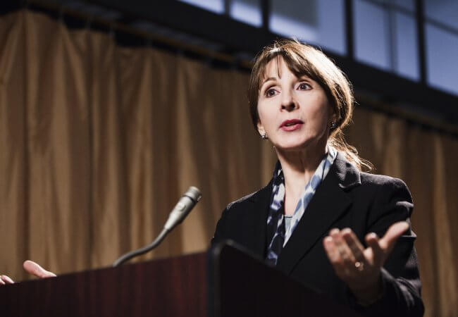 Caucasian woman standing at a podium, as a public health nurse leader