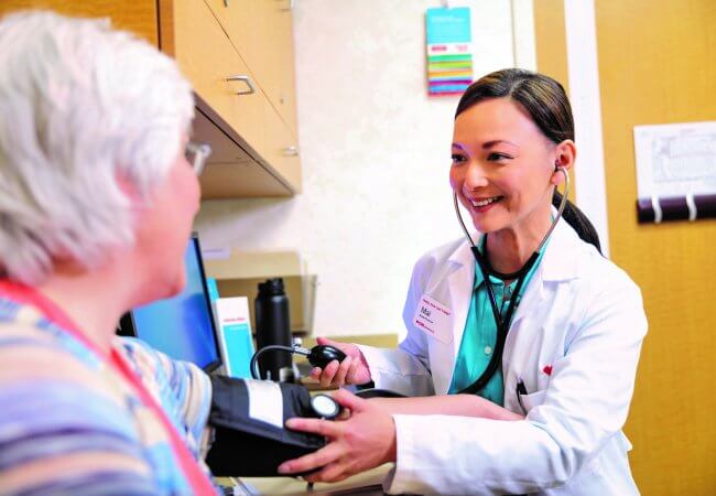 CVS MinuteClinic is rolling out “Age-Friendly” care for its older adult customers. Nurse practitioner Mai is taking the blood pressure of a patient. 